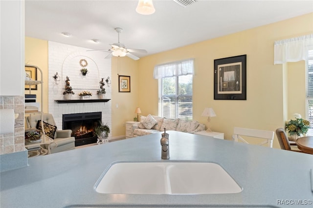 kitchen with a ceiling fan and a brick fireplace