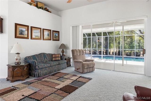 carpeted living area with a ceiling fan and a sunroom