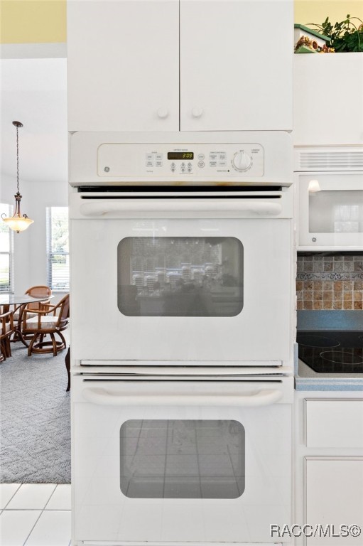 room details with white cabinets, white appliances, carpet floors, decorative light fixtures, and decorative backsplash