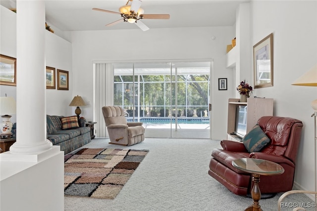 carpeted living room with ornate columns and ceiling fan