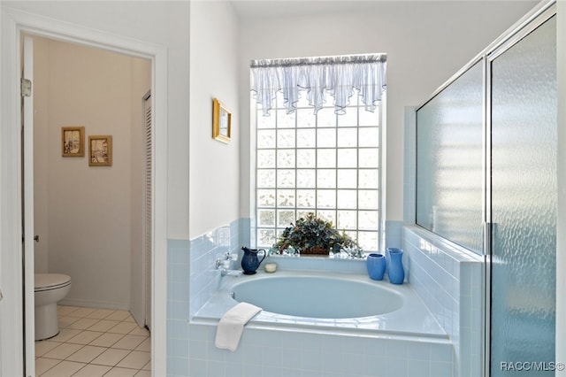 full bathroom featuring toilet, baseboards, tile patterned flooring, and a garden tub