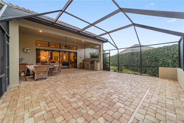 view of patio featuring an outdoor kitchen, a grill, and glass enclosure