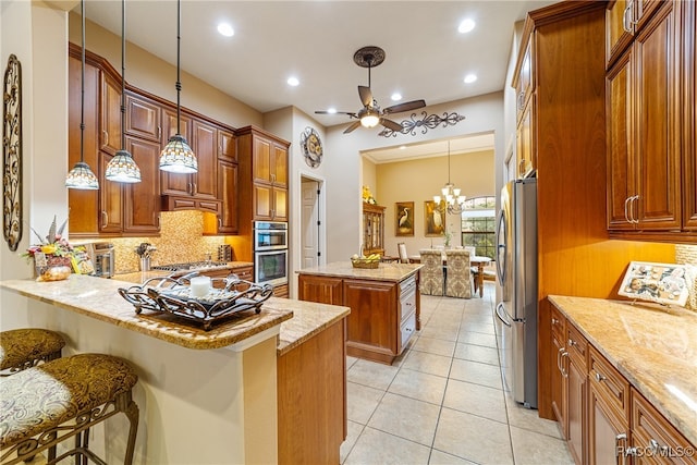 kitchen featuring kitchen peninsula, appliances with stainless steel finishes, a kitchen island, hanging light fixtures, and a breakfast bar area