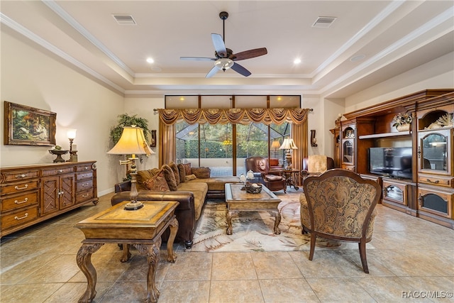 tiled living room with a tray ceiling, ceiling fan, and ornamental molding