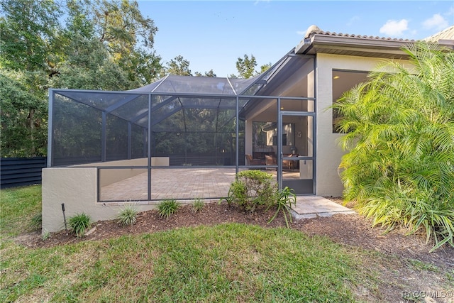 back of property with a patio and glass enclosure