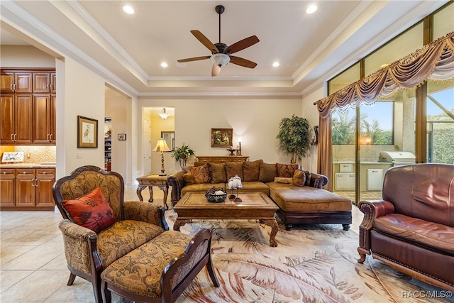 tiled living room featuring a raised ceiling, ceiling fan, and crown molding