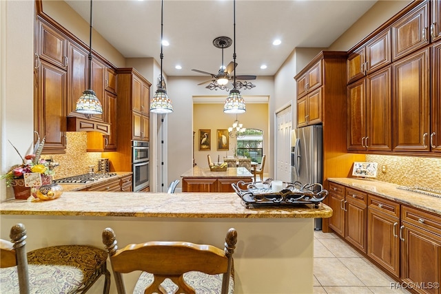 kitchen featuring decorative light fixtures, a kitchen bar, light stone counters, and stainless steel appliances