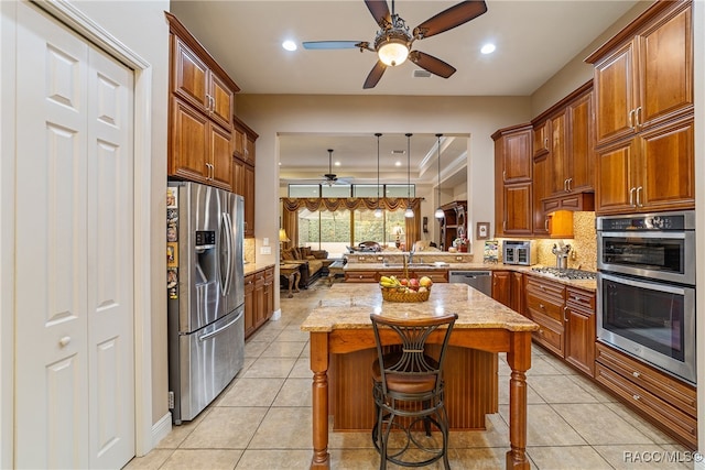 kitchen featuring light stone countertops, appliances with stainless steel finishes, a kitchen island, a kitchen bar, and kitchen peninsula