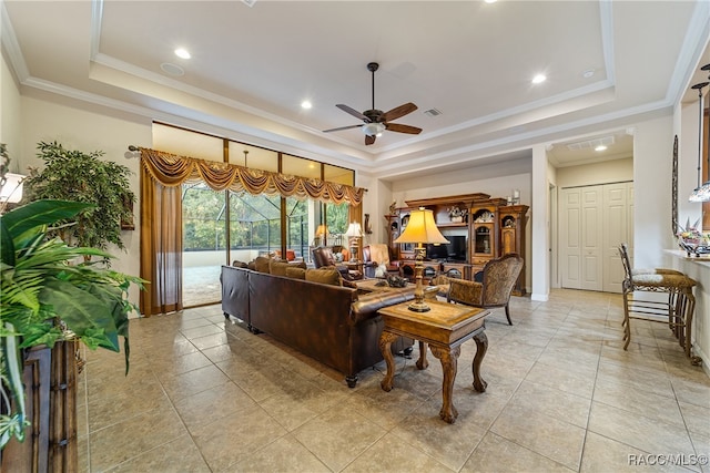 living room featuring ceiling fan, light tile patterned flooring, ornamental molding, and a tray ceiling