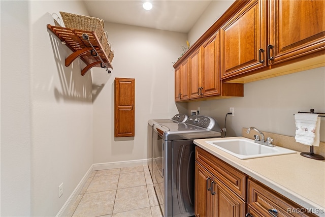 laundry room with washer and clothes dryer, cabinets, light tile patterned floors, and sink