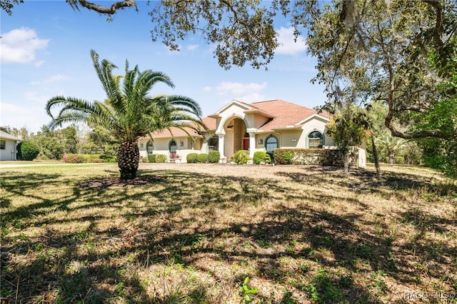 mediterranean / spanish-style home featuring a front yard and stucco siding