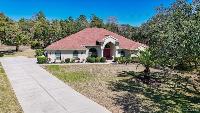 mediterranean / spanish home featuring stucco siding, driveway, and a front yard