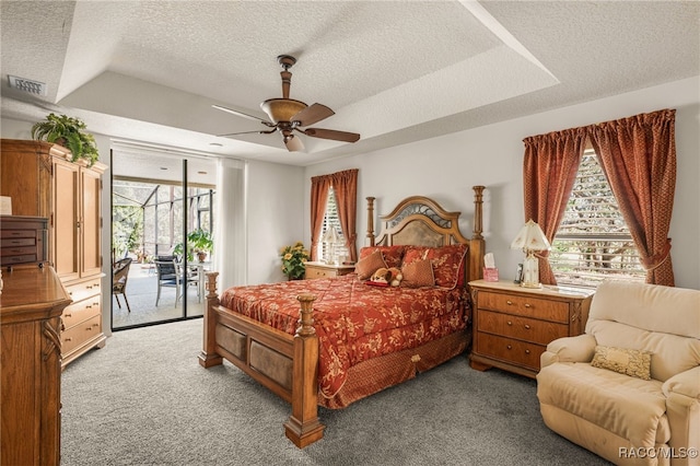 carpeted bedroom featuring a raised ceiling, access to outside, visible vents, and a textured ceiling