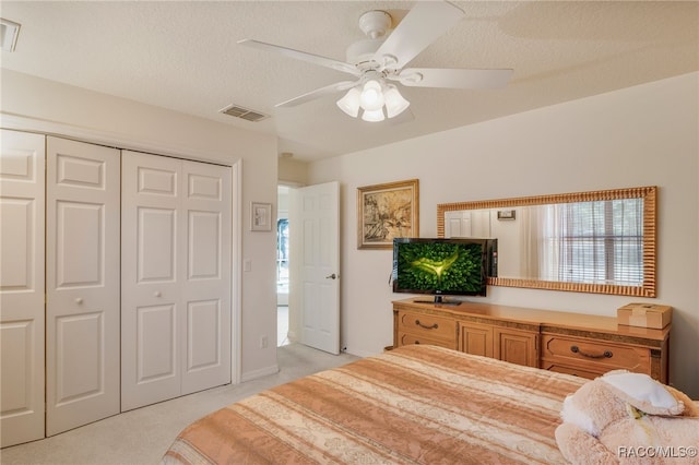 bedroom with visible vents, light carpet, a closet, a textured ceiling, and a ceiling fan