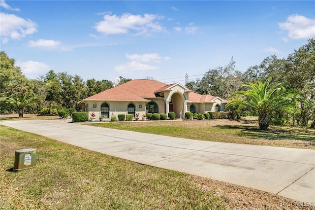 mediterranean / spanish-style house featuring stucco siding, concrete driveway, and a front lawn