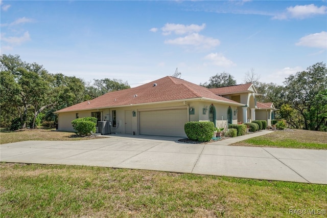 view of front of home featuring an attached garage, central AC, stucco siding, concrete driveway, and a front lawn