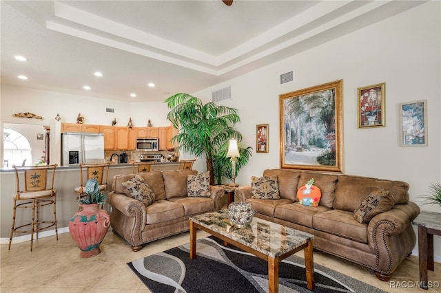 living room featuring visible vents, recessed lighting, and a raised ceiling