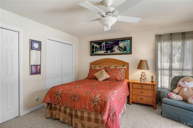 bedroom featuring carpet, baseboards, ceiling fan, a textured ceiling, and two closets