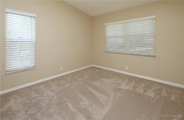 carpeted spare room featuring vaulted ceiling