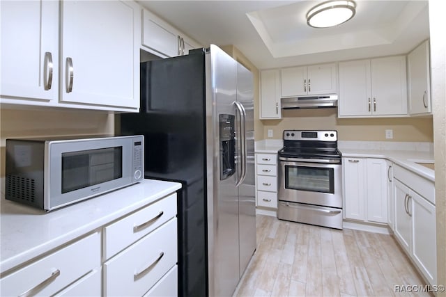 kitchen featuring light hardwood / wood-style floors, a raised ceiling, white cabinetry, and stainless steel appliances