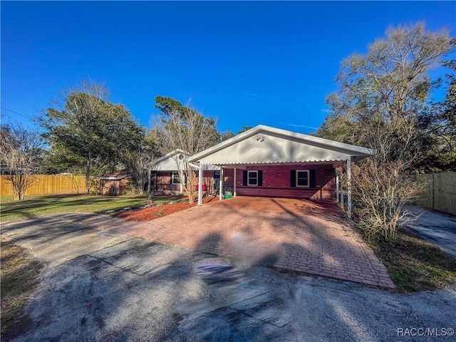 view of front of property with a carport, decorative driveway, fence, and a front lawn