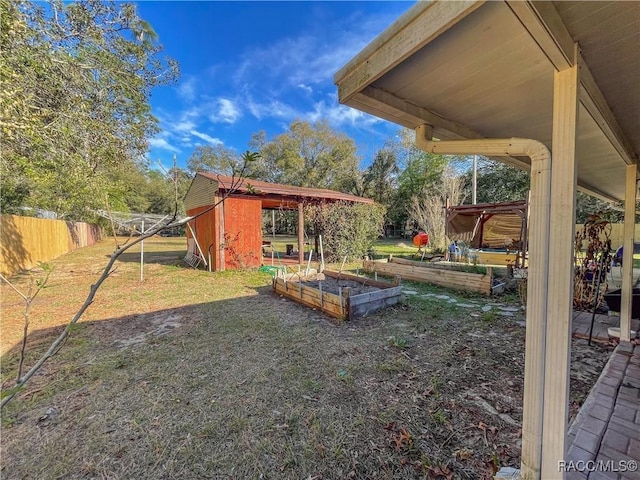 view of yard featuring an outbuilding, fence, and a garden