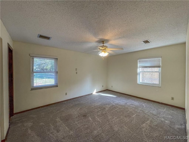 carpeted spare room with a ceiling fan, visible vents, and baseboards