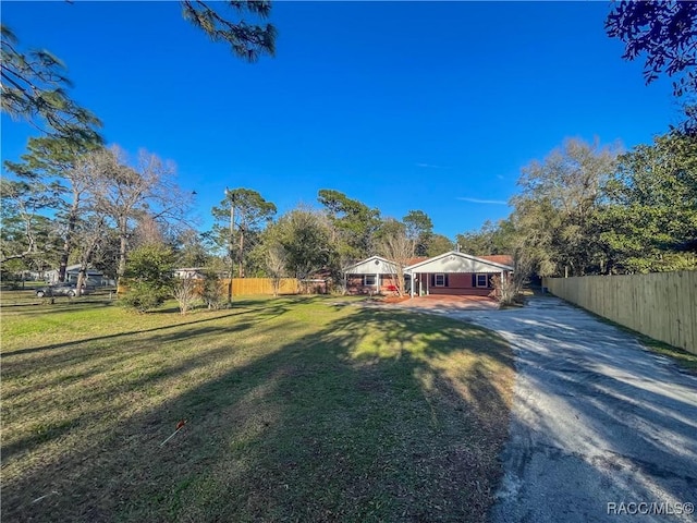 view of front facade with driveway, a front lawn, and fence