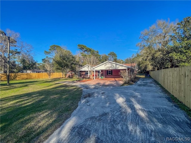 view of front facade featuring driveway, fence, and a front yard