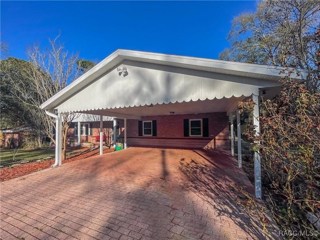 view of front facade with a carport, decorative driveway, and brick siding