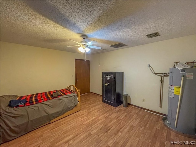 bedroom featuring ceiling fan, water heater, visible vents, and wood finished floors