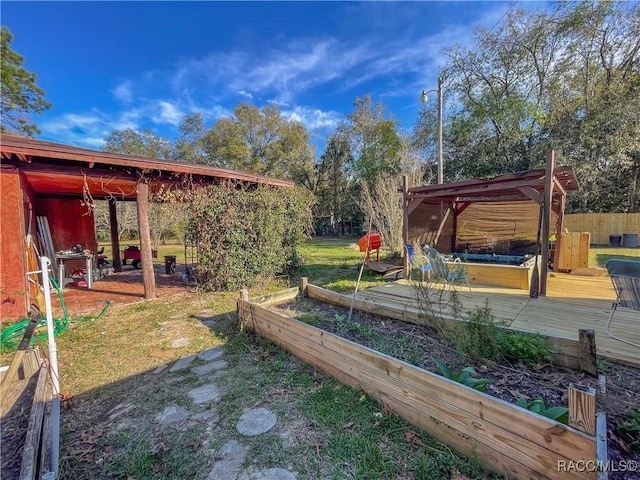 view of yard featuring fence, a vegetable garden, and a deck