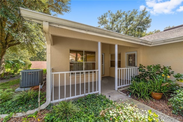 view of exterior entry with cooling unit and covered porch