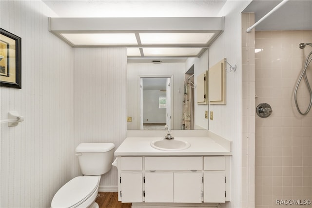 bathroom with tiled shower, wood-type flooring, vanity, and toilet