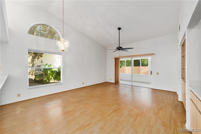 unfurnished living room with ceiling fan with notable chandelier, high vaulted ceiling, and light hardwood / wood-style flooring