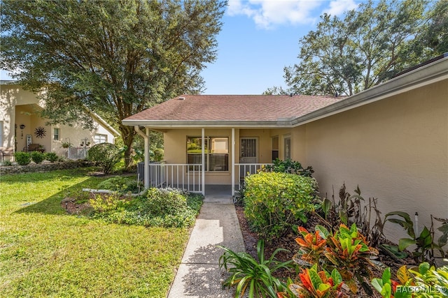 entrance to property with covered porch and a yard