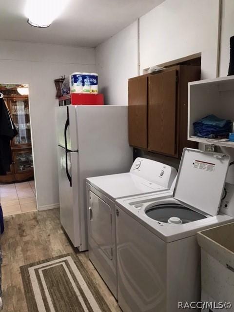 laundry area with cabinets, light hardwood / wood-style floors, washer and clothes dryer, and sink