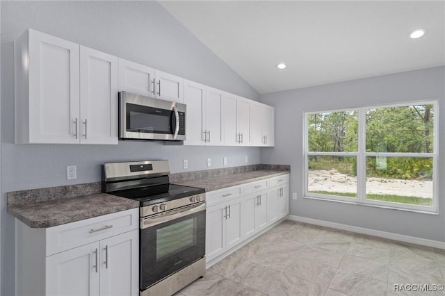 kitchen featuring appliances with stainless steel finishes, vaulted ceiling, and white cabinets