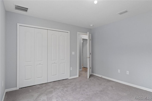 unfurnished bedroom with light carpet and a closet