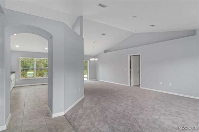 carpeted spare room featuring vaulted ceiling and a notable chandelier