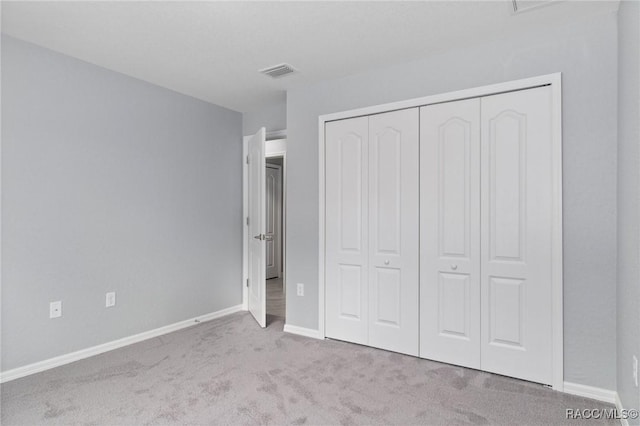 unfurnished bedroom with light colored carpet and a closet