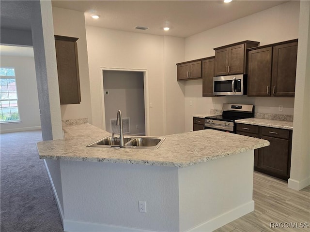 kitchen with dark brown cabinetry, sink, appliances with stainless steel finishes, kitchen peninsula, and light hardwood / wood-style floors