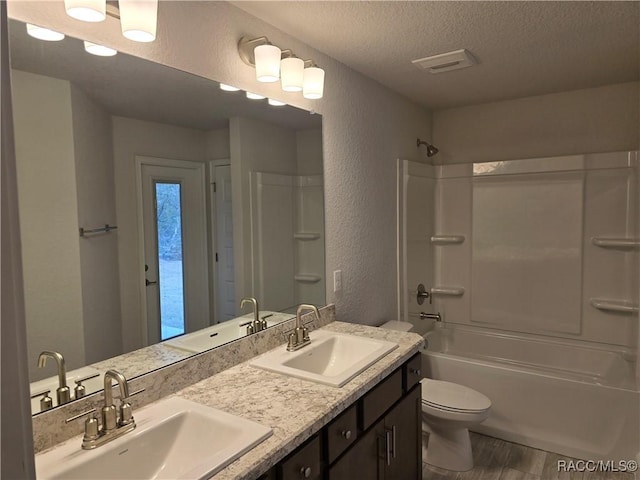 full bathroom with toilet, wood-type flooring, a textured ceiling, shower / bathtub combination, and vanity