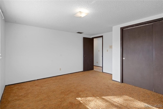 unfurnished bedroom featuring light carpet, a closet, and a textured ceiling