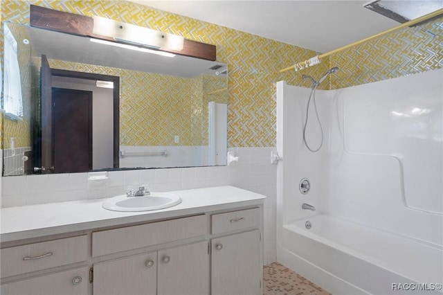 bathroom featuring vanity, washtub / shower combination, and tile walls