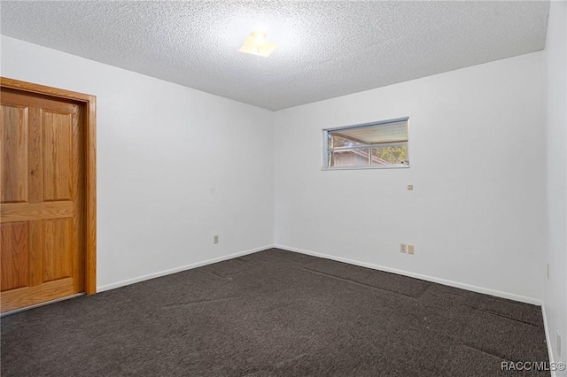 empty room with dark carpet and a textured ceiling