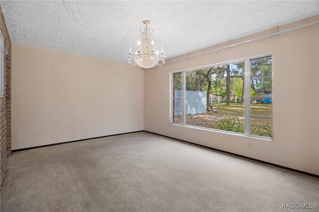 carpeted spare room featuring a chandelier and a textured ceiling