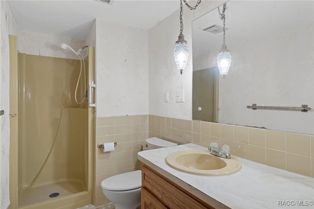 bathroom featuring vanity, toilet, tile walls, and walk in shower