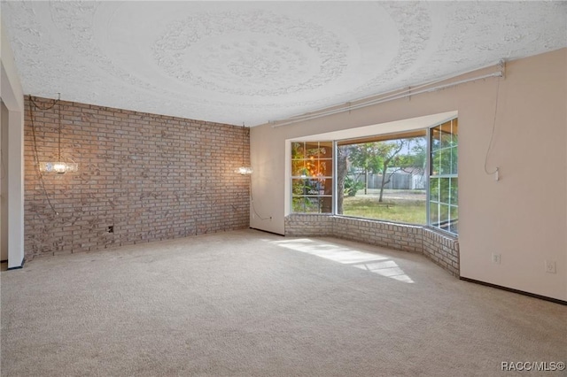 empty room with a raised ceiling and brick wall