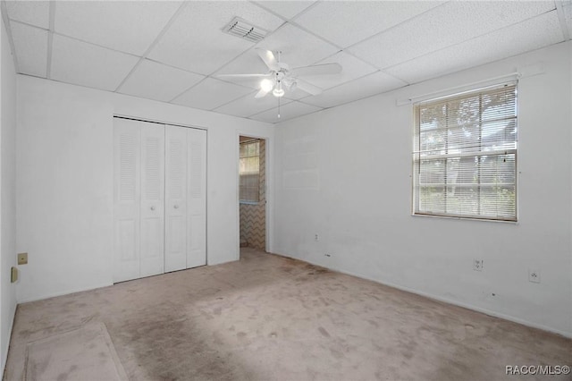 unfurnished bedroom featuring light carpet, a paneled ceiling, a closet, and ceiling fan